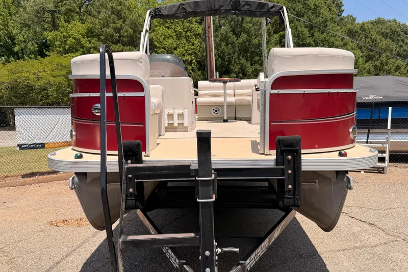 Slide: The Image of 2013 Veranda 24 pontoon boat on trailer, red and white design, parked outdoors. - 2