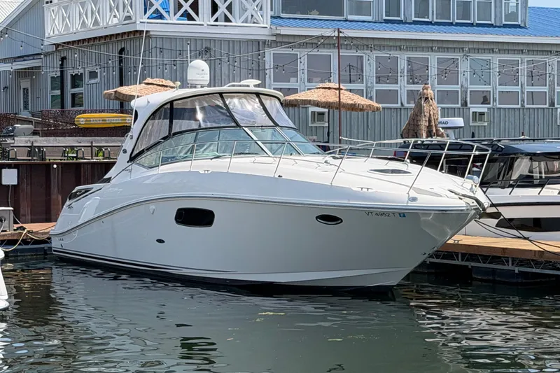 The Image of 2011 Sea Ray Sundancer 370 docked at marina, with waterfront building in background. - 0