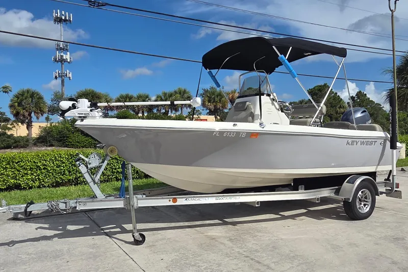 Slide: The Image of 2022 Key West 189 FS boat on trailer with canopy, parked outdoors. - 14
