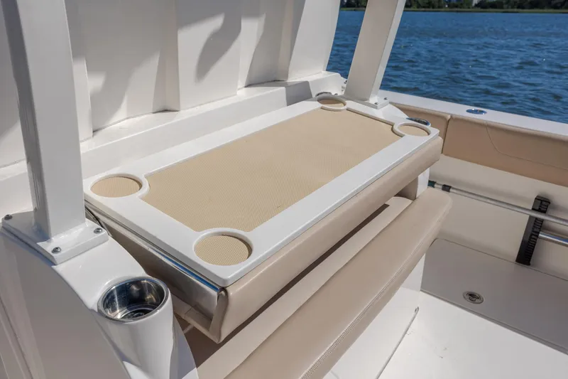 Slide: The Image of 2019 Scout 355 LXF boat interior with cup holders and seating by the water. - 16