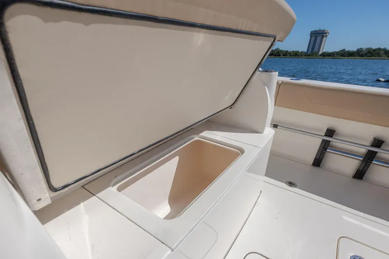 Slide: The Image of 2019 Scout 355 LXF boat storage compartment open on deck by the water. - 15