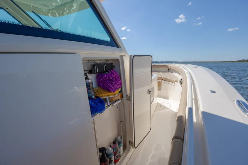 Slide: The Image of 2019 Scout 355 LXF boat with open storage compartment on a sunny day. - 27
