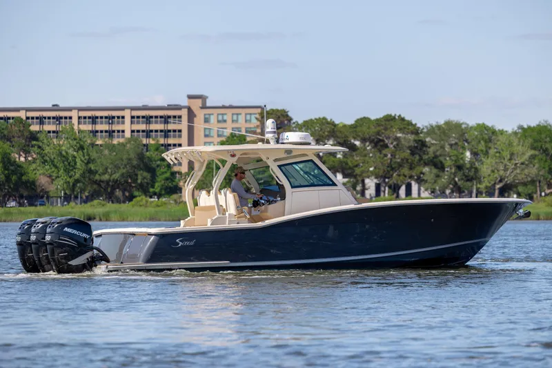 Slide: The Image of 2019 Scout 355 LXF boat cruising on a calm river with lush greenery in the background. - 2