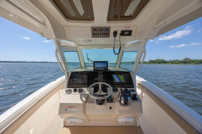 Slide: The Image of 2019 Scout 355 LXF boat helm with navigation screens on open water. - 20