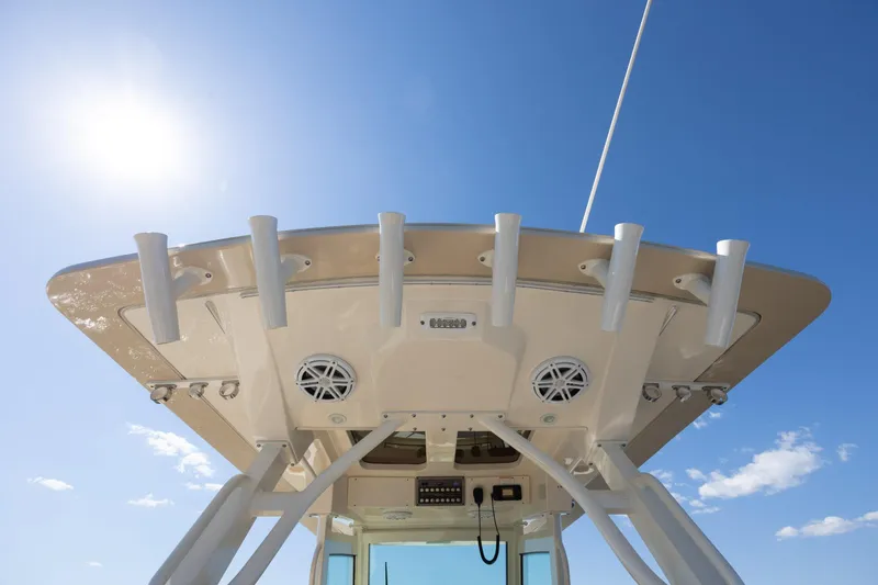 Slide: The Image of 2019 Scout 355 LXF boat top view with rod holders and speakers under clear sky. - 19