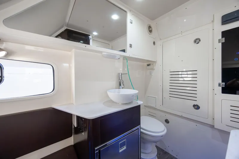 Slide: The Image of 2019 Scout 355 LXF boat interior bathroom with sink, toilet, and storage cabinets. - 38