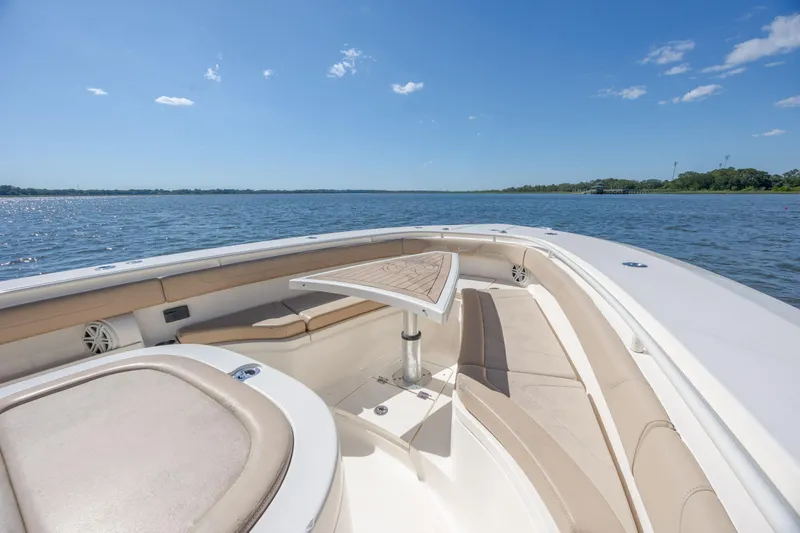 Slide: The Image of 2019 Scout 355 LXF boat interior with seating and table on a sunny day. - 30