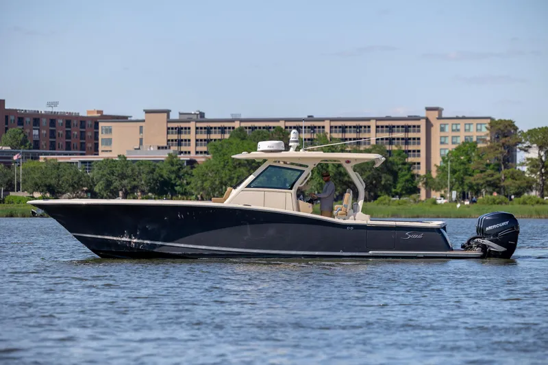 Slide: The Image of 2019 Scout 355 LXF boat cruising on a calm river near urban buildings. - 6