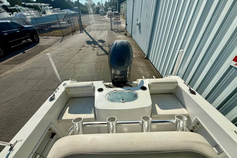 Slide: The Image of 2012 Sea Hunt Triton 210 boat with outboard motor, docked near a metal building. - 9