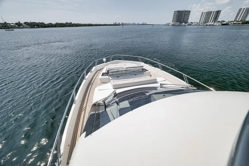 Slide: The Image of 2022 Galeon 560 Fly yacht cruising on a serene waterway with city skyline views. - 71