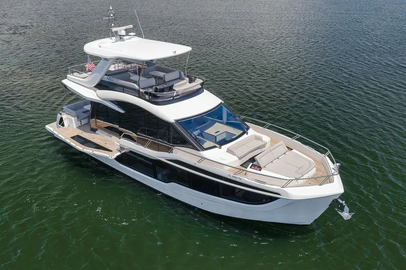 Slide: The Image of 2022 Galeon 560 Fly yacht on calm water, showcasing sleek design and spacious deck. - 12