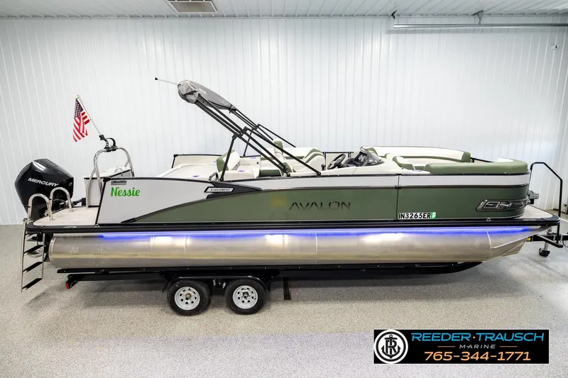 The Image of 2024 Avalon CAT VRB pontoon boat with green accents in a showroom. - 1