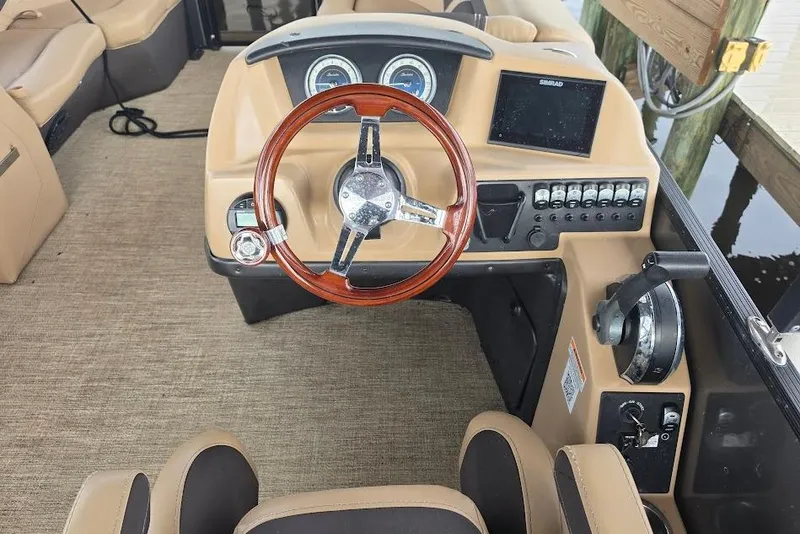 Slide: The Image of 2022 Barletta Cabrio 24UE boat dashboard with wood steering wheel and control panel. - 13