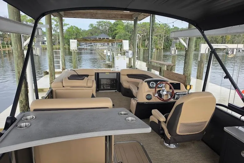 Slide: The Image of Interior of 2022 Barletta Cabrio 24UE pontoon boat at dock, featuring helm and seating. - 8