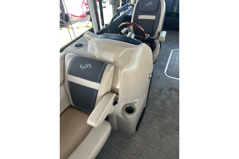 Slide: The Image of 2022 Barletta Cabrio 24UE boat interior with beige and black seating, steering wheel, and cup holders. - 37