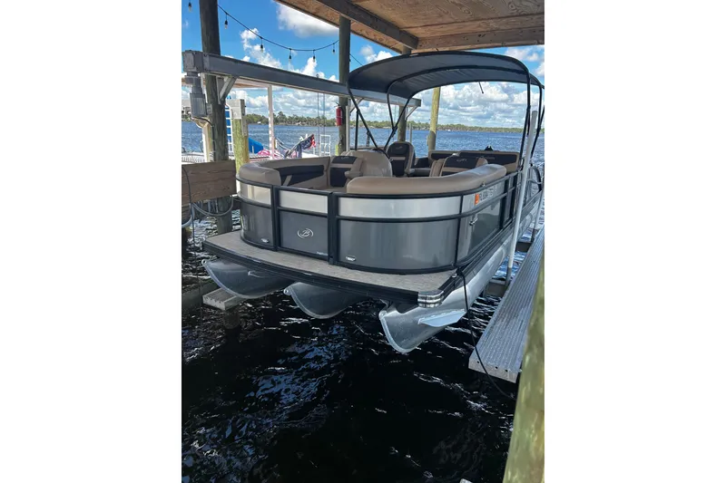 Slide: The Image of 2022 Barletta Cabrio 24UE pontoon boat docked under a wooden canopy. - 3
