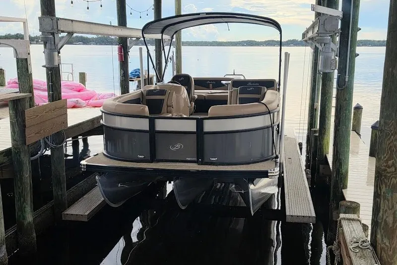 Slide: The Image of 2022 Barletta Cabrio 24UE pontoon boat docked on a serene lake. - 2