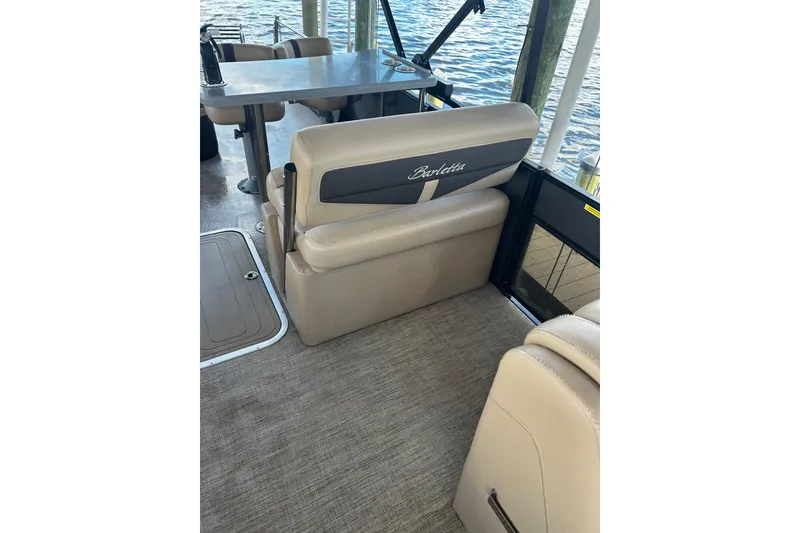 Slide: The Image of 2022 Barletta Cabrio 24UE boat interior with beige seating and table by the water. - 36