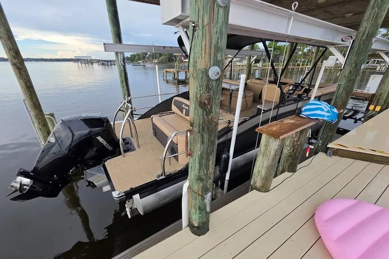 Slide: The Image of 2022 Barletta Cabrio 24UE pontoon boat docked by wooden pier. - 6
