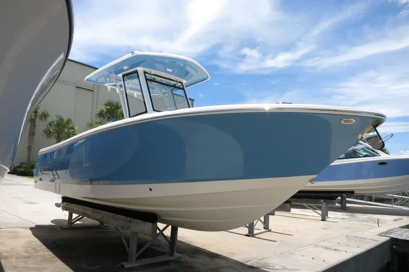 Slide: The Image of 2026 Robalo R250 Center Console boat in blue, displayed outdoors on a sunny day. - 2