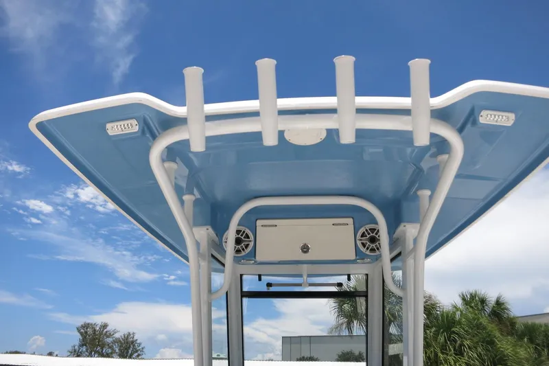 Slide: The Image of 2026 Robalo R250 Center Console boat's T-top with rod holders and speakers against blue sky. - 18