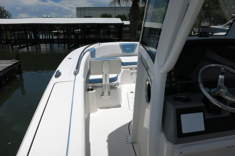 Slide: The Image of 2026 Robalo R250 Center Console boat interior with steering wheel and seating, docked by the water. - 21
