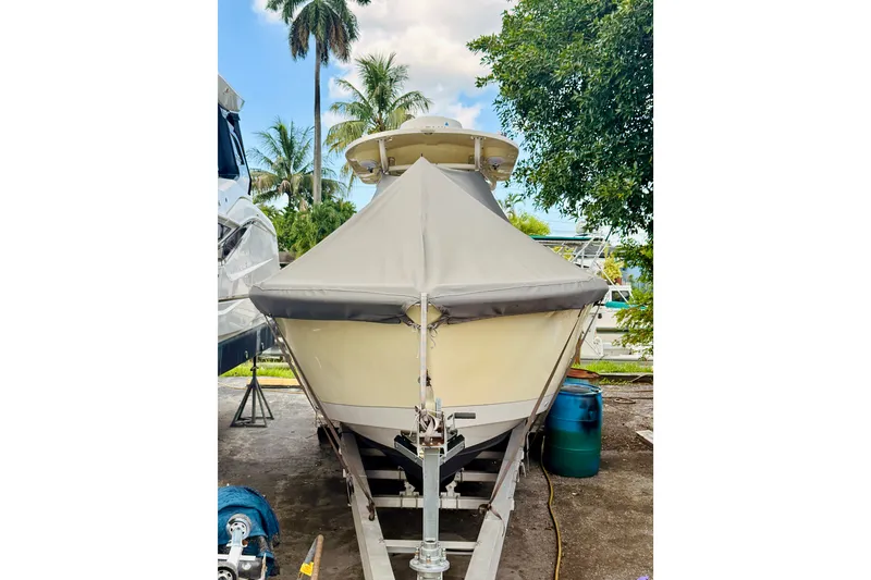 Slide: The Image of 2018 Sea Chaser 27 HFC CC boat on trailer, covered, with palm trees in background. - 3