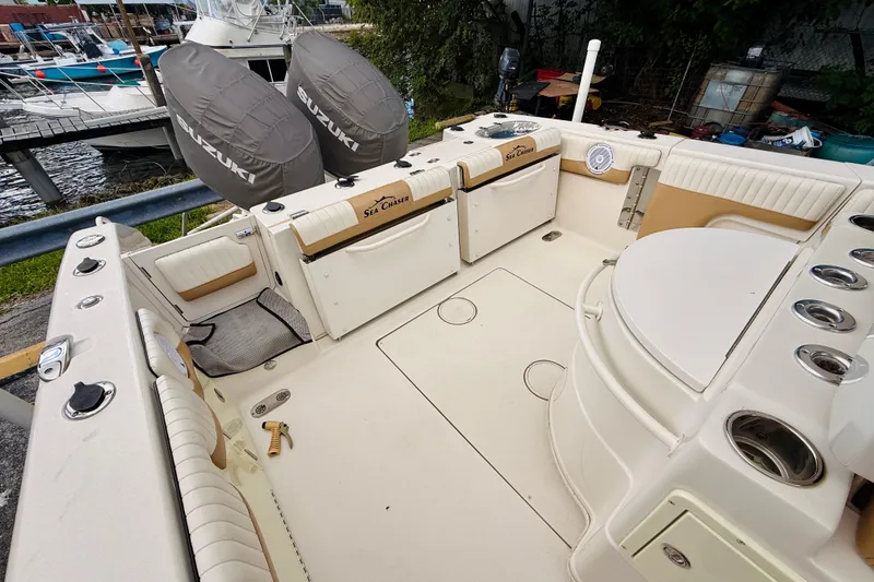 Slide: The Image of 2018 Sea Chaser 27 HFC CC boat interior with Suzuki engines, docked near water. - 18