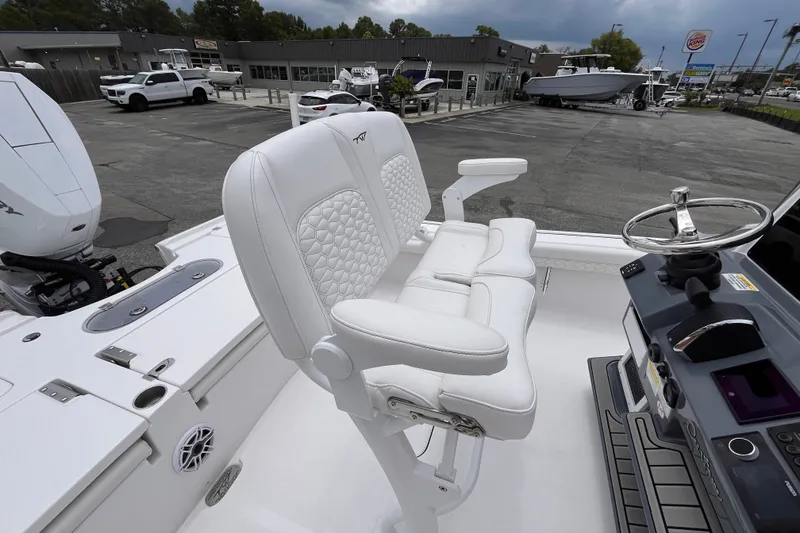 Slide: The Image of 2027 Tidewater 2500 Carolina Bay boat with white seating and steering wheel in a dealership lot. - 7
