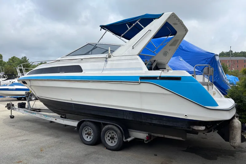 Slide: The Image of 1992 Bayliner 2850 Contessa boat on trailer, featuring blue and white design. - 2