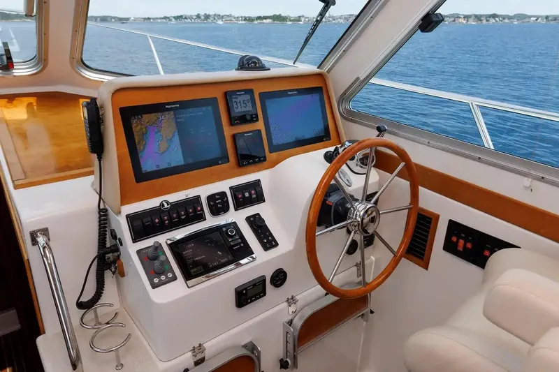 Slide: The Image of 2017 Back Cove Yachts 37 helm with navigation screens and steering wheel, overlooking the ocean. - 36