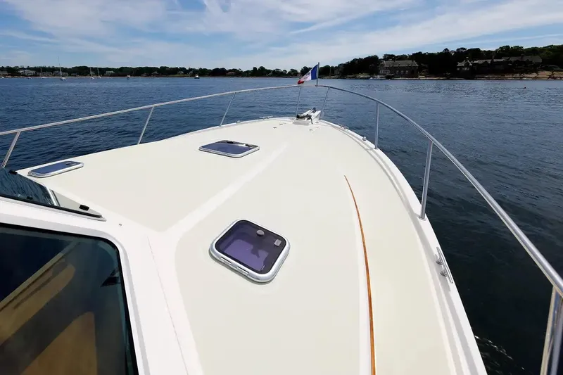 Slide: The Image of 2017 Back Cove Yachts 37 on calm water, showcasing sleek deck design and scenic shoreline. - 18