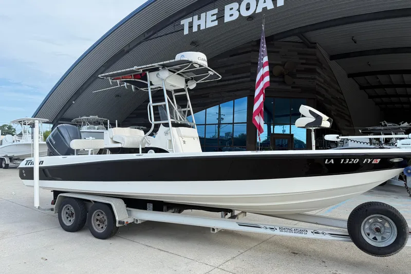 Slide: The Image of 2008 Triton 240 LTS boat on trailer outside a showroom with American flag. - 2