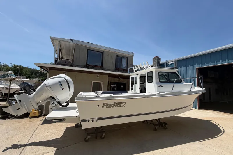 Slide: The Image of 2027 Parker 227 Explorer boat with Yamaha engine, parked outside a building. - 2