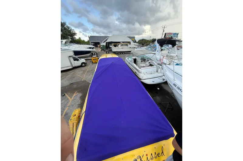 Slide: The Image of 1999 Fountain 47 Lightning boat with blue cover in a marina setting. - 2