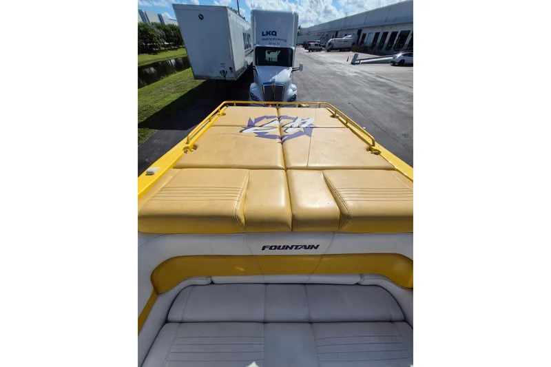 Slide: The Image of 1999 Fountain 47 Lightning boat with yellow upholstery, parked near a truck and warehouse. - 17