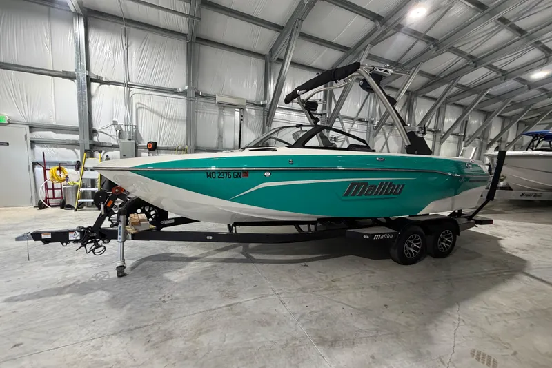 Slide: The Image of 2022 Malibu Wakesetter 23 LSV boat in a storage facility, teal and white design. - 1