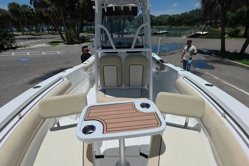 Slide: The Image of 2017 Sea Fox 226 Commander boat interior with seating and table, parked near a scenic waterfront. - 34
