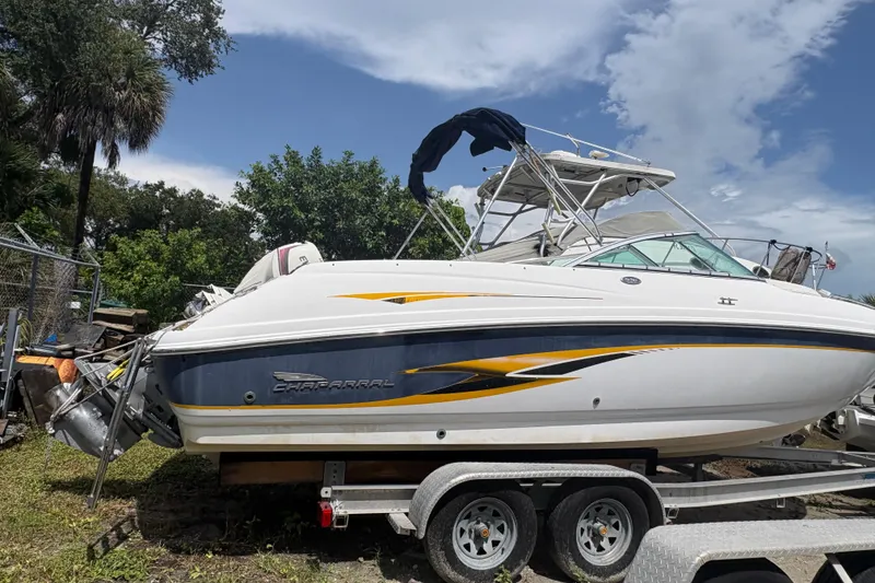 Slide: The Image of Chaparral 230 SSi 2000 boat on trailer, parked outdoors under a partly cloudy sky. - 15