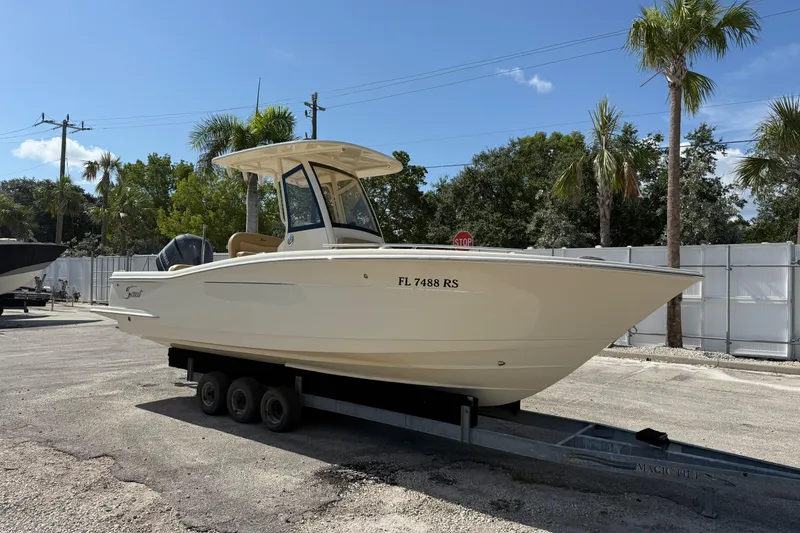 Slide: The Image of 2018 Scout 235 XSF boat on trailer, parked outdoors under clear sky. - 1