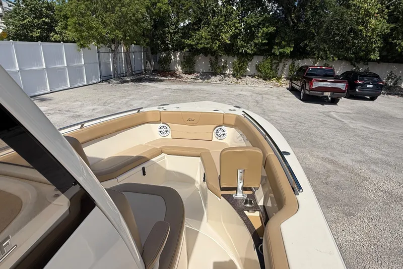 Slide: The Image of 2018 Scout 235 XSF boat interior with tan seating, parked in a lot. - 9
