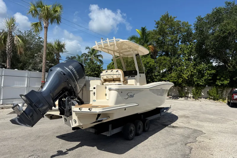 Slide: The Image of 2018 Scout 235 XSF boat with Yamaha engine on trailer, surrounded by palm trees. - 2