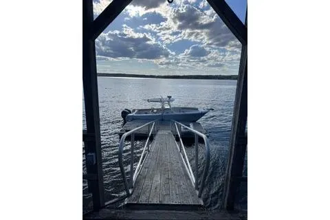 Slide: The Image of 2012 Sailfish 3180 CC boat docked on a serene lake under a cloudy sky. - 5