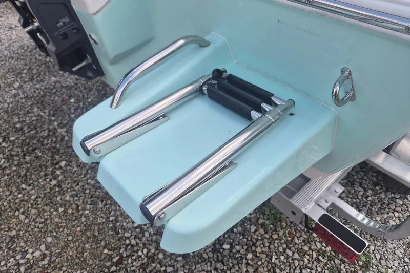 Slide: The Image of 2026 Key West 210 Bay Reef boat ladder on light blue hull, resting on gravel. - 4