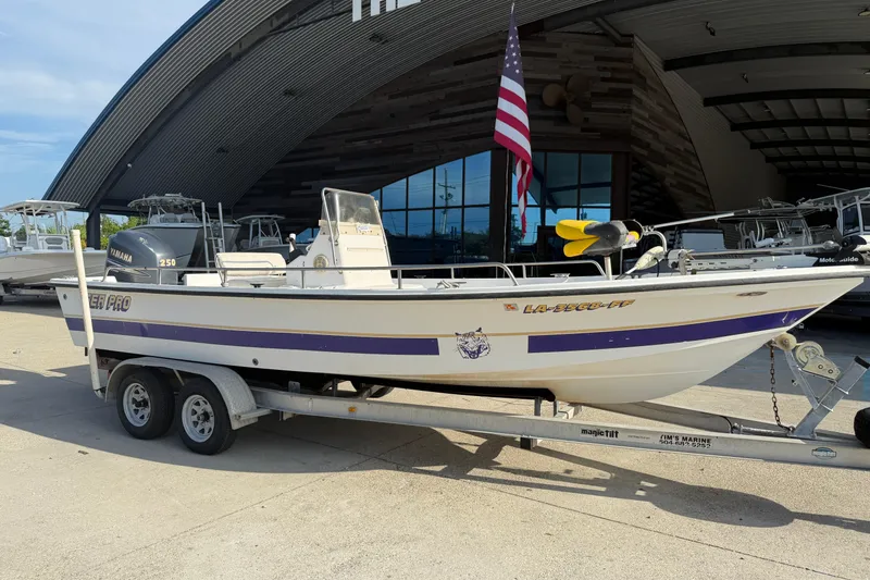 Slide: The Image of 2002 Sea Pro SV2400CC Bay Boat on trailer, parked outside a marine facility. - 2