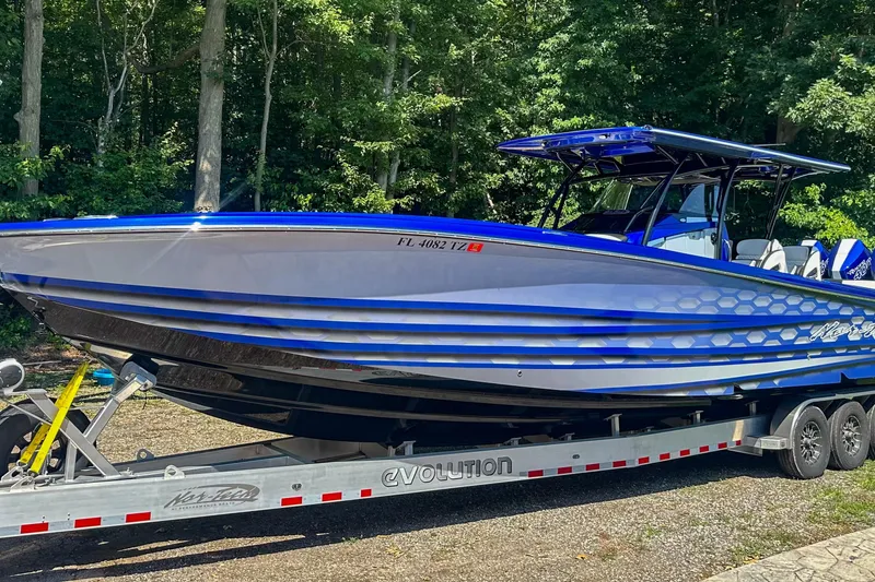 Slide: The Image of 2025 Nor-Tech 390 Sport Center Console boat on trailer, parked in wooded area. - 3