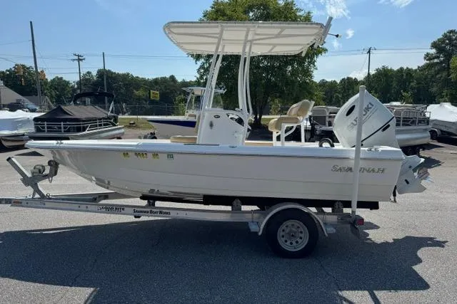 Slide: The Image of 2022 Savannah 190 IS boat on trailer, featuring a T-top and outboard motor. - 2