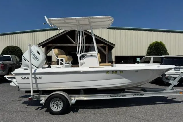 The Image of 2022 Savannah 190 IS boat on trailer, featuring Suzuki outboard motor, parked outdoors. - 0