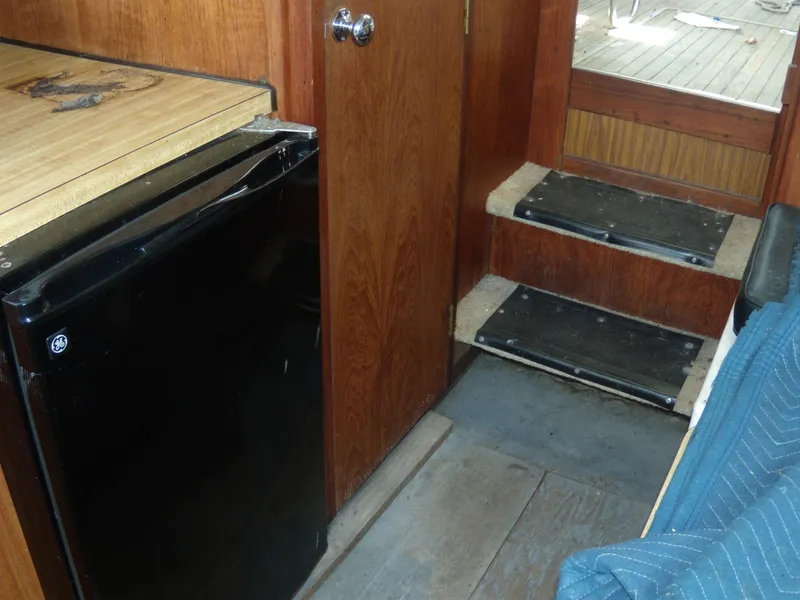 Slide: The Image of Interior of a 1973 Trojan F-32 with wood paneling, a small fridge, and steps. - 9
