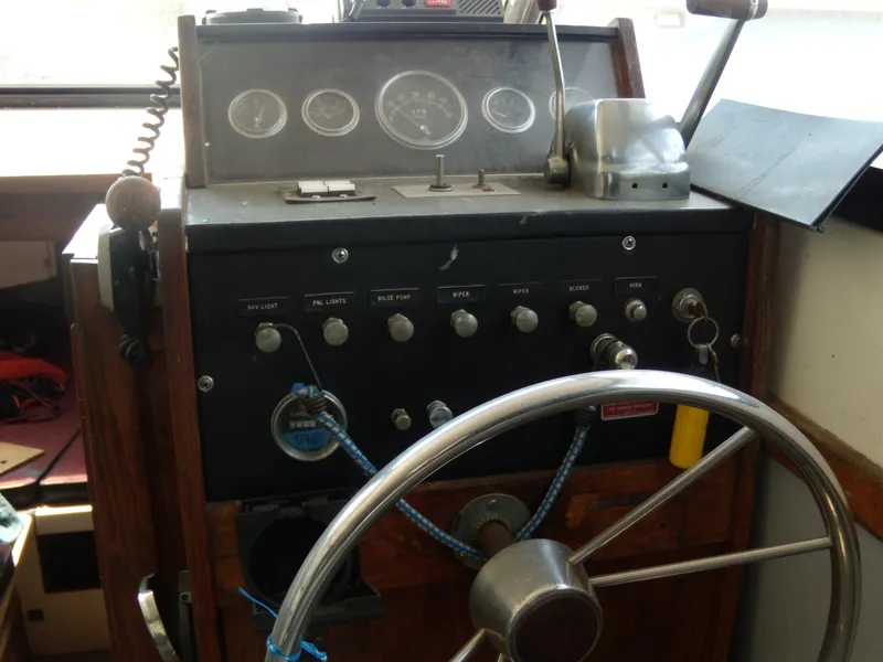 Slide: The Image of The image shows the helm of a 1973 Trojan F-32 boat with a wooden steering wheel and various instruments. - 11